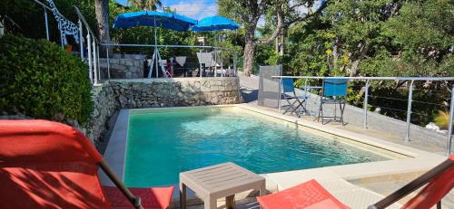 une piscine avec chaises et parasols dans une cour dans l'établissement Minoury, à Mandelieu-la-Napoule
