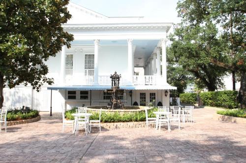 a large white house sitting in front of some trees at The Magnolia Mansion in New Orleans