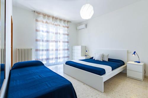 2 bedden in een witte kamer met blauwe lakens bij Appartamento Bellariva B1-MyHo Casa in Porto San Giorgio