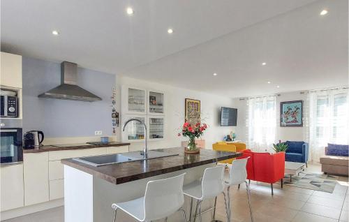 une cuisine avec un îlot de cuisine avec des armoires blanches et des chaises rouges dans l'établissement Amazing Home In Marennes, à Marennes