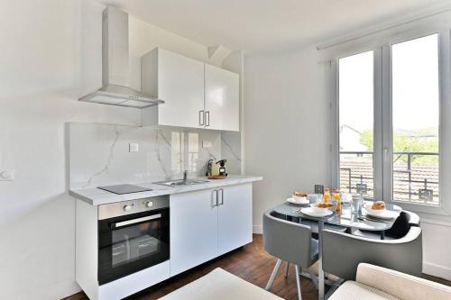 une cuisine avec des armoires blanches et une table et une salle à manger dans l'établissement Peaceful Apartment next to Paris Gagny - II, à Gagny