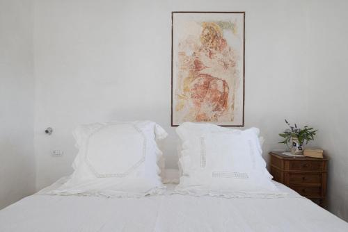 a white bed with white pillows and a picture on the wall at Masseria Le Torri in Polignano a Mare