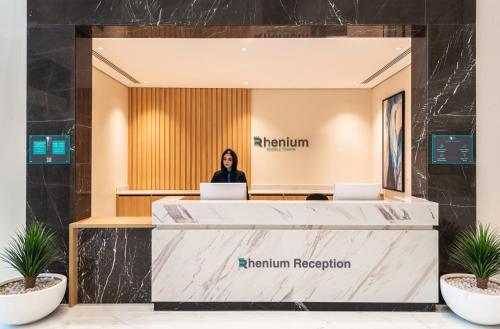 a woman sitting at a reception desk with two laptops at Rhenium Hotel in Riyadh
