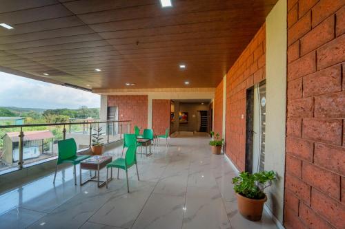 a patio with green chairs and tables and a brick wall at Treebo Iceberg in Mahabaleshwar