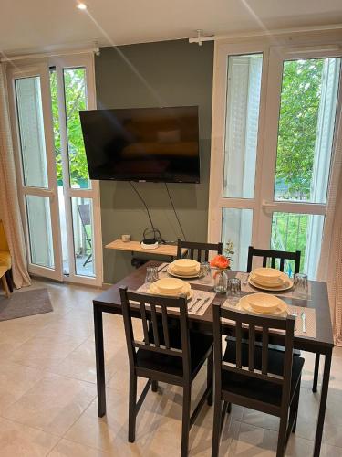 une salle à manger avec une table avec des chaises et une télévision dans l'établissement Kalaban - Moderne - Paris, CDG, Disney, Expo Parc, à Gagny