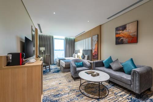 a living room with a couch and a tv at Rhenium Hotel in Riyadh