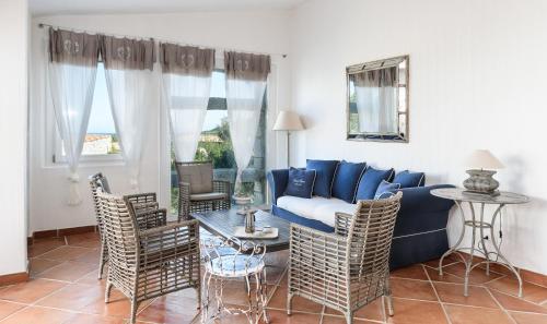 a living room with a blue couch and chairs at Villa Li Conchi 34 in Cala Sinzias