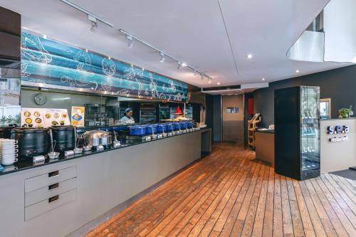 een restaurant met een bar en een chef-kok die maaltijden bereidt bij Hotel Baraquda Heeton Pattaya by Compass Hospitality in Pattaya