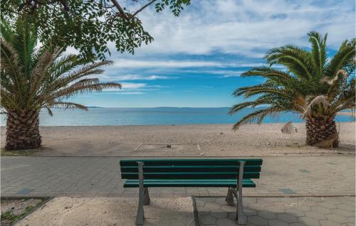 a green bench on a beach with palm trees at Beach Front Apartment In Kosljun in Košljun