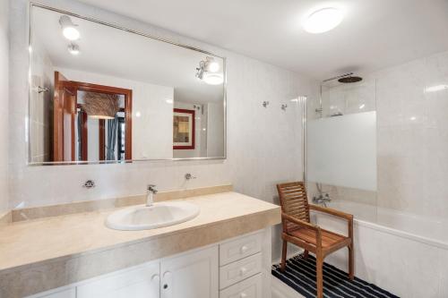 a bathroom with a sink and a mirror and a chair at Casa Papaya in El Médano