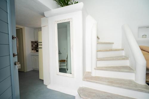 a white hallway with stairs and a mirror at 5 Traditional Suites in Livadi Astypalaias