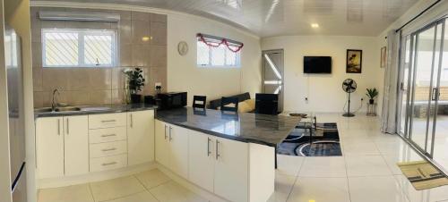a large kitchen with white cabinets and a living room at The MK House in Cape Town