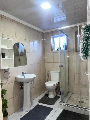 a bathroom with a toilet and a shower and a sink at The MK House in Cape Town