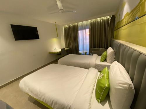 a hotel room with two beds and a television at Le Roi Dehradun at Dehradun Railway Station in Dehradun