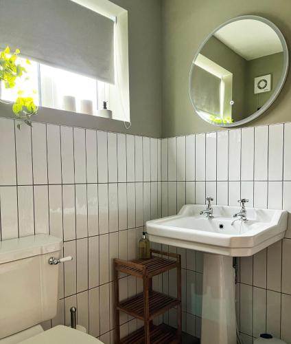 a bathroom with a sink and a mirror and a toilet at Boutique style cosy cottage in Ellesmere