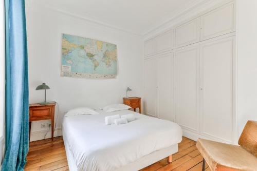 une chambre blanche avec un lit et une chaise dans l'établissement GuestReady - Séjour paisible à Paris, à Paris