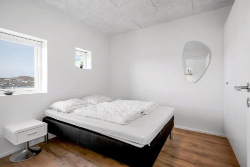 a white bedroom with a bed and a window at Feriehus 1042 in Ringkøbing