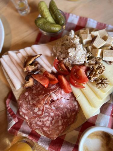 a plate of food with meat and cheese and vegetables at Chalet Tisa Velika Planina in Stahovica