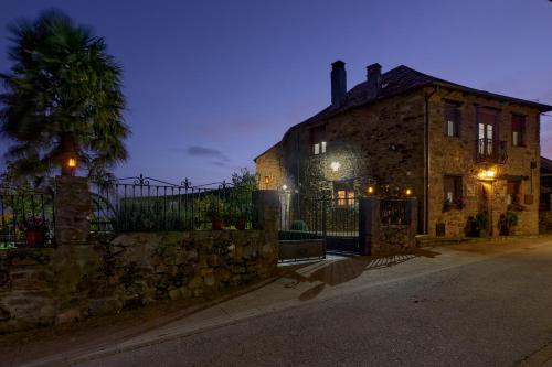 an old stone house with a fence and a palm tree at Casa Rural Abuelo Jose in Robledo de las Traviesas