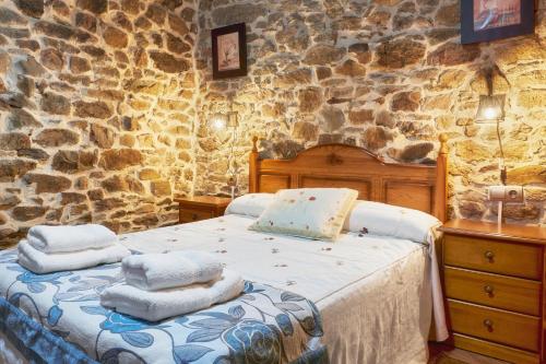 a bedroom with a bed and a stone wall at Casa Rural Abuelo Jose in Robledo de las Traviesas