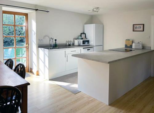 une cuisine avec des armoires blanches et un réfrigérateur blanc dans l'établissement Woodland Cottage Charleton Estate, à Colinsburgh