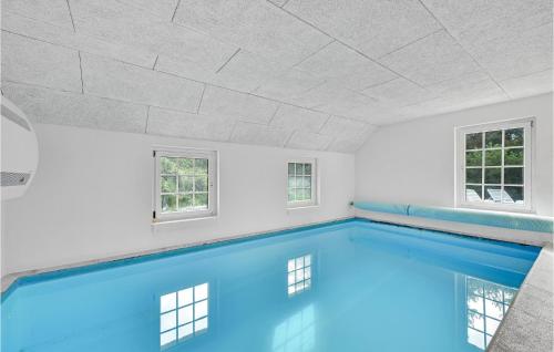 a swimming pool in a white room with windows at Stunning Home In Ringkøbing With Sauna in Søndervig