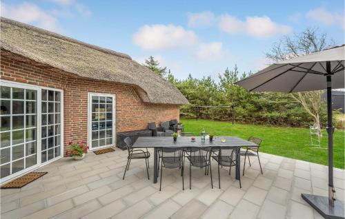 a patio with a table and chairs and an umbrella at Stunning Home In Ringkøbing With Sauna in Søndervig