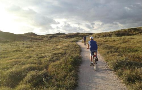 two people riding bikes down a dirt road at Stunning Home In Ringkøbing With Sauna in Søndervig
