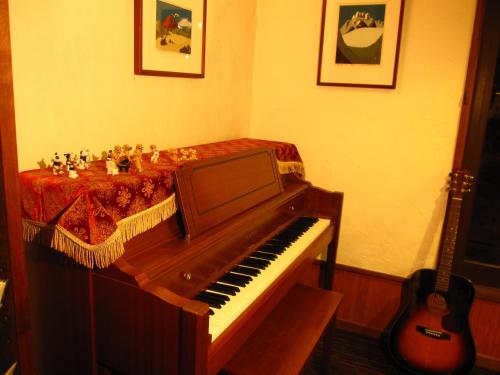 a piano sitting in a room with a guitar at Hakuba Skala Inn in Hakuba