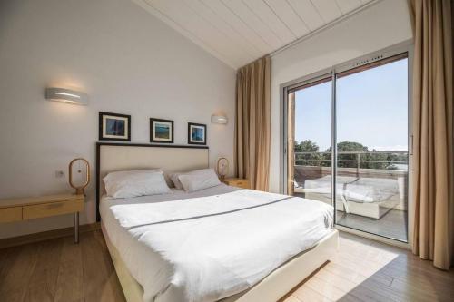une chambre avec un grand lit et une grande fenêtre dans l'établissement Appartement 4* piscine et plage à pied, à Porto-Vecchio
