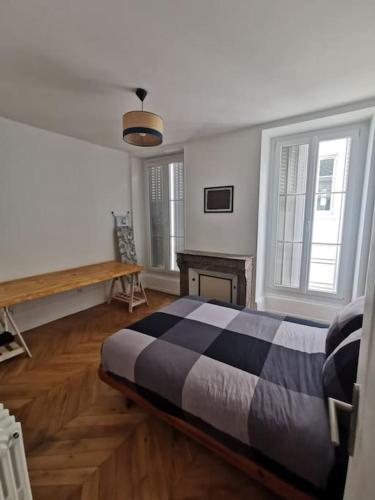 une chambre avec un lit et une table et deux fenêtres dans l'établissement La voûte de Jeanne, à Orléans