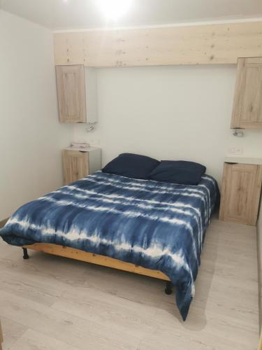 - un lit avec une couette bleue dans l'établissement Petite maison de village charmante et authentique, à Aniane