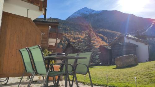 a table and chairs on a patio with a mountain at Studio au pied de la télécabine, SaastalCards Saas-Fee in Saas-Fee