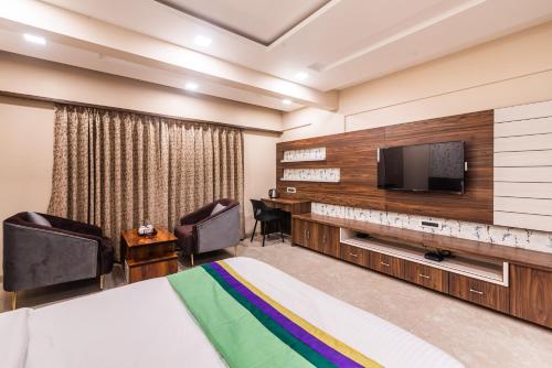 a hotel room with a bed and a flat screen tv at Lemon wood suites in Pune