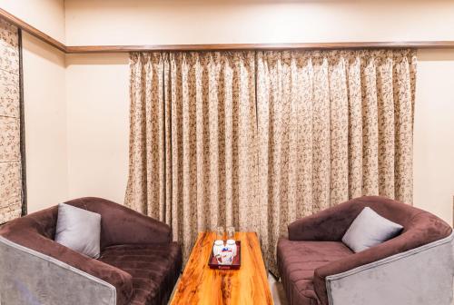 a living room with two chairs and a wooden table at Lemon wood suites in Pune