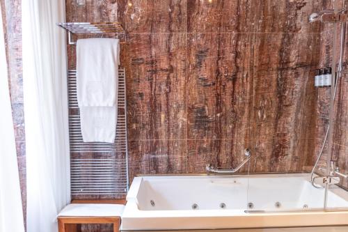 a bath tub in a bathroom with a wooden wall at Mirador de Dalt Vila-Relais & Chateaux in Ibiza Town