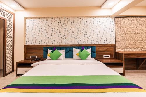 a bedroom with a large bed with blue and green pillows at Lemon wood suites in Pune