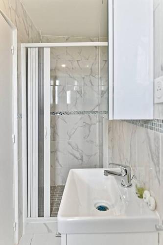 une salle de bain blanche avec un lavabo et une douche dans l'établissement Appartement moderne proche Paris - Gagny - III, à Gagny