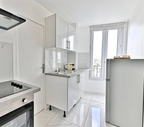 une cuisine blanche avec un réfrigérateur et une fenêtre dans l'établissement Appartement moderne proche Paris - Gagny - III, à Gagny