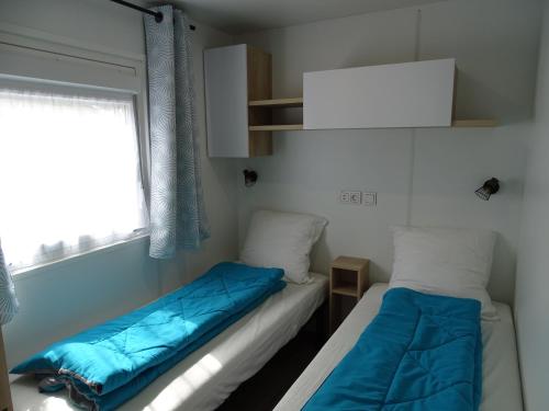 deux lits dans une chambre avec une fenêtre dans l'établissement Escape MobilHome aux Dunes de Contis, à Saint-Julien-en-Born