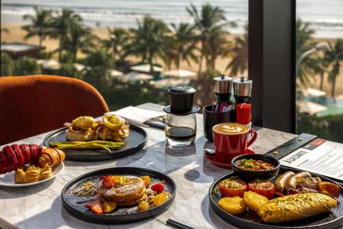 岘港Radisson RED Danang的餐桌上摆放着食物盘的桌子,海滩上摆放着