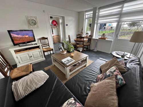 a living room with a couch and a tv at Het Tinkerparadijs, paarden, rust en ruimte. in Burgh Haamstede