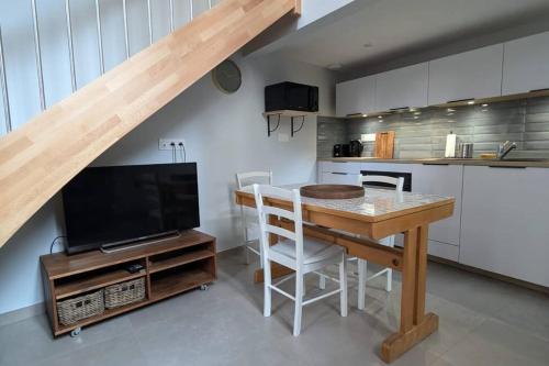 - une cuisine avec une table, une télévision et un comptoir dans l'établissement L'Atelier d'Henri centre-ville Annonay, à Annonay