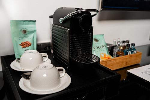 a coffee maker and two cups on a counter at Mirador de Dalt Vila-Relais & Chateaux in Ibiza Town
