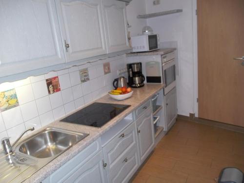 a kitchen with white cabinets and a sink and a microwave at Ferienhaus am Ringweg in Bad Schandau