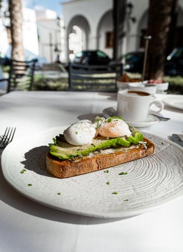 a sandwich with eggs on a white plate on a table at Mirador de Dalt Vila-Relais & Chateaux in Ibiza Town
