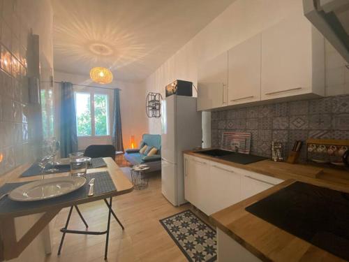 une cuisine avec une table et un réfrigérateur blanc dans l'établissement Appartement proche de la gare, à Montpellier