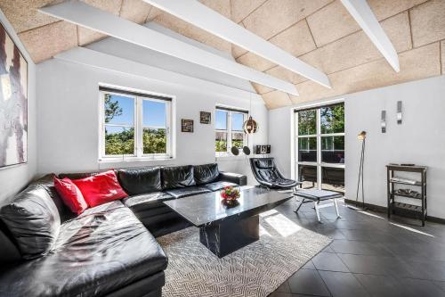 a living room with a black leather couch and a table at Beautiful Holiday Home With Spa And Sauna, Close To The North Sea And The Center Of Søndervig in Ringkøbing