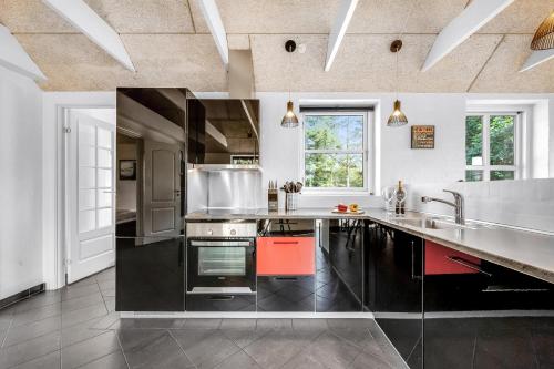 a large kitchen with black and white counter tops at Beautiful Holiday Home With Spa And Sauna, Close To The North Sea And The Center Of Søndervig in Ringkøbing