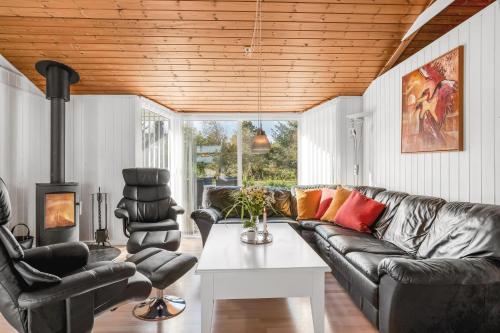 a living room with a leather couch and two chairs at Lovely Spa House In Scenic Surroundings in Thyholm